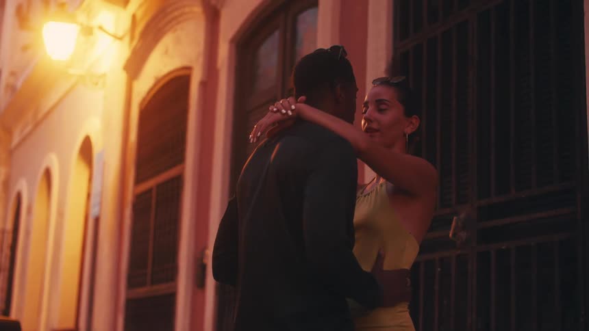 Couple stand close kissing in front of chained gate
