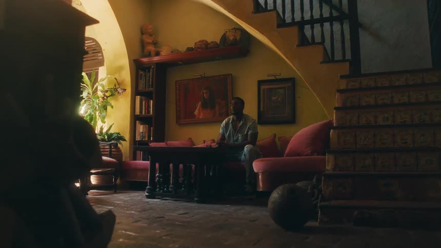 A young man is sitting down on a couch inside of his home