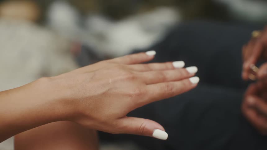 Man slides ring onto womans hand during a proposal then kisses the hand