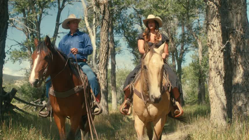 Two people are riding a horse in a field of grass
