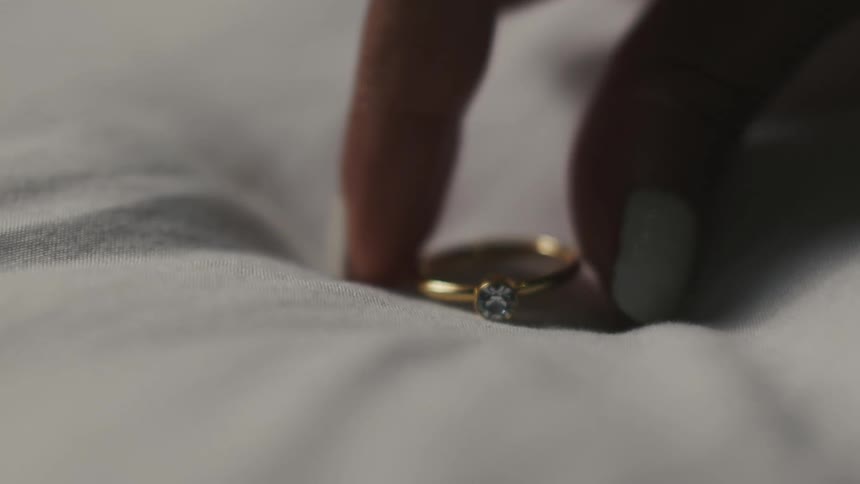 Close up of hand putting down ring on bed