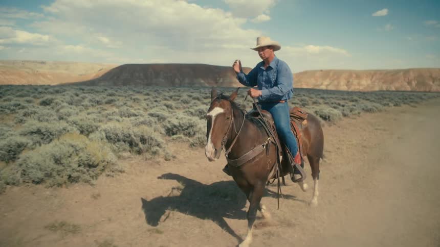 Cowboy rides a horse on a road through the desert at daytime