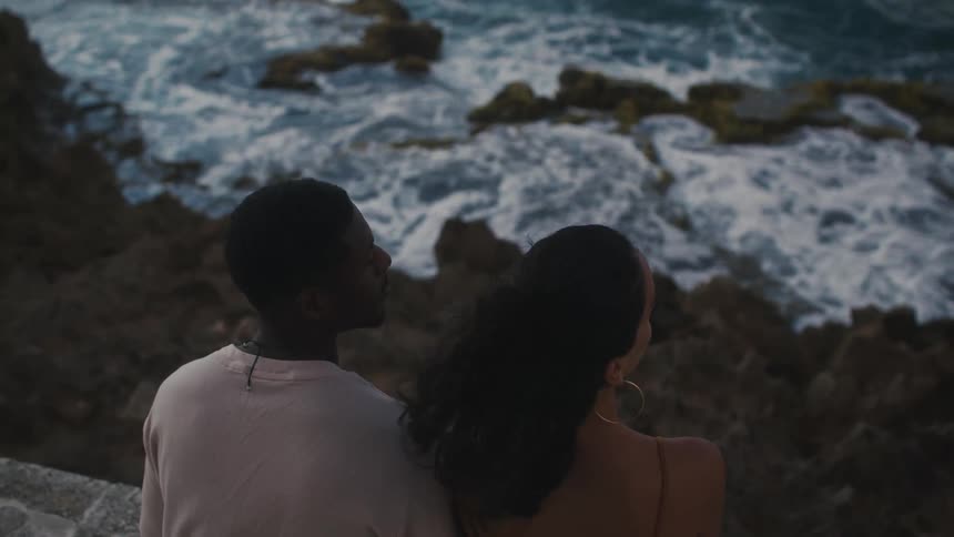 Couple watching the coastline from ledge above