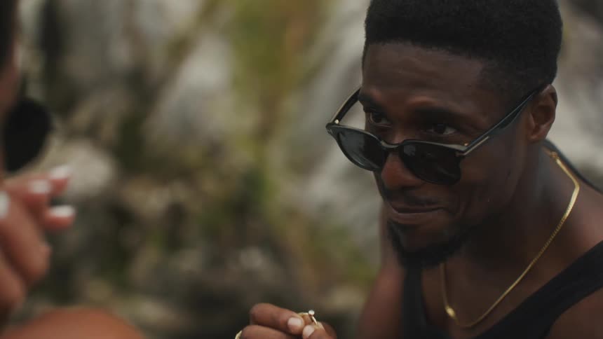 Young man kneels in front of his fiancee to propose with a wedding ring