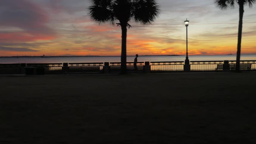A man is jogging along the boardwalk at dawn