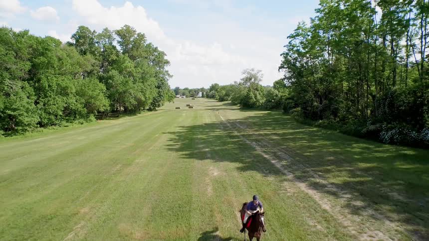 A horse rider is racing down a grass field