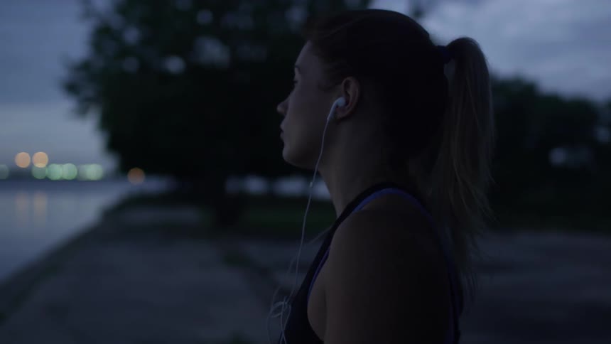 A woman puts earbuds in while walking