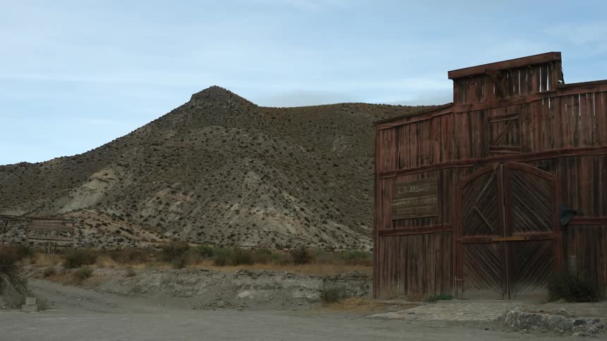 A view of an old barn at a ghost town and a desert mountain behind