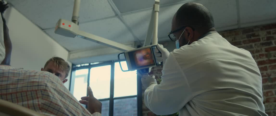 Dentist wearing glasses and mask uses dental light for the patient