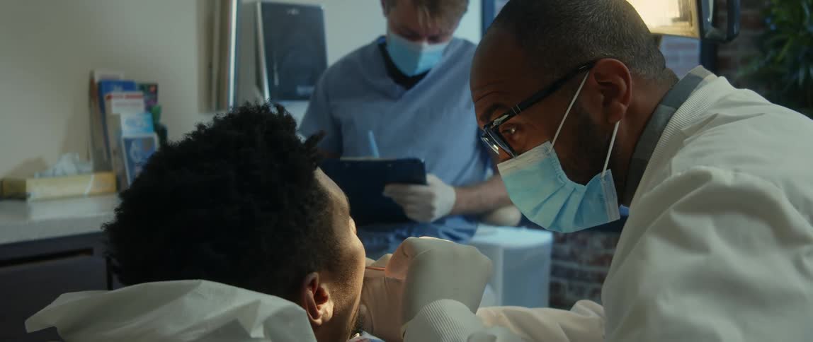 Dental technician takes notes while dentist examines patients teeth