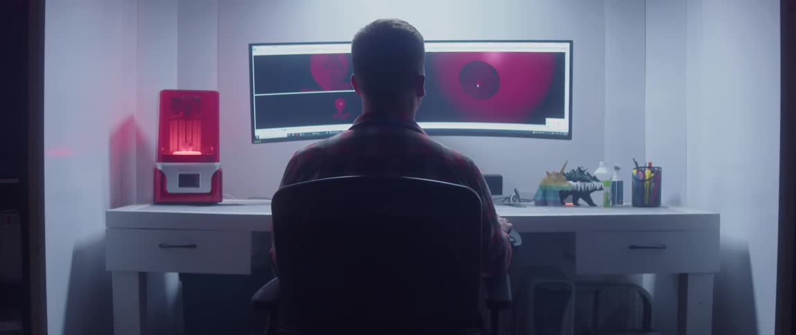 A young white man is sitting in front of his computer and designing a 3D object