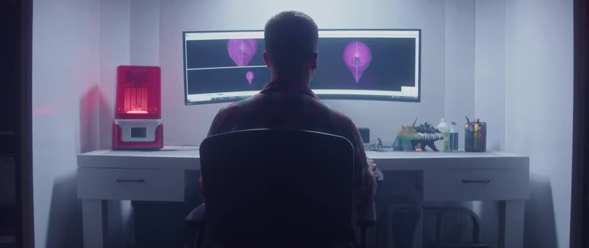 Man with plaid shirt sits at desk working on computer