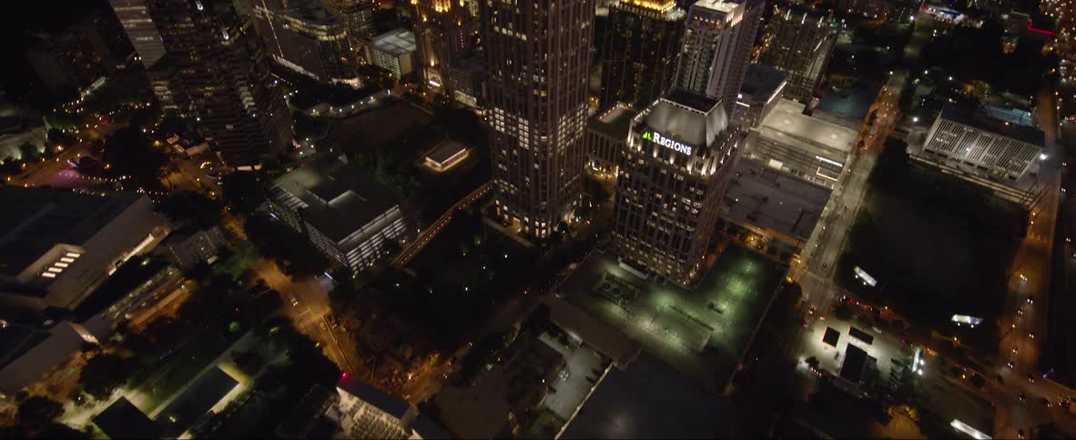 High rise office buildings in a city at night as cars drive down the city streets