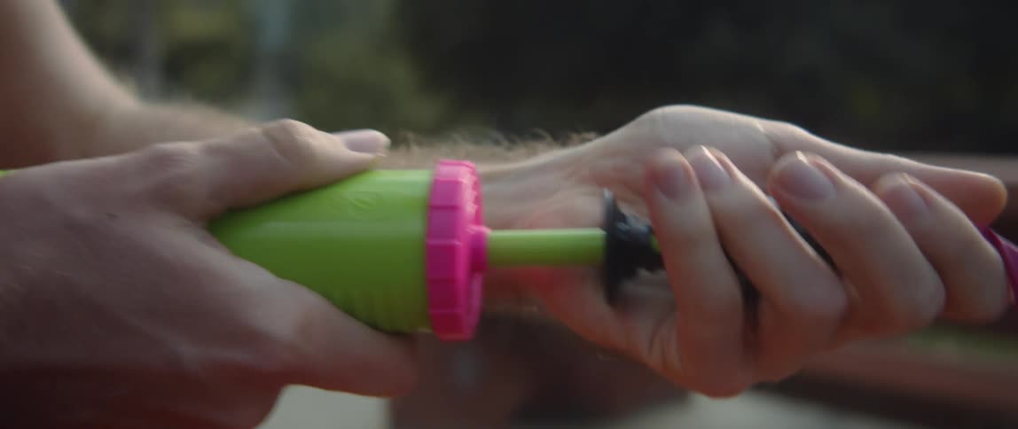 A man filling a hot pink balloon with a hand pump