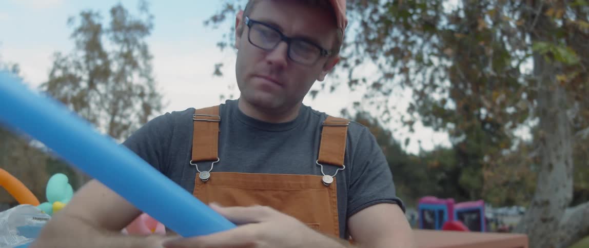 A man creates balloon animals for a party in a park