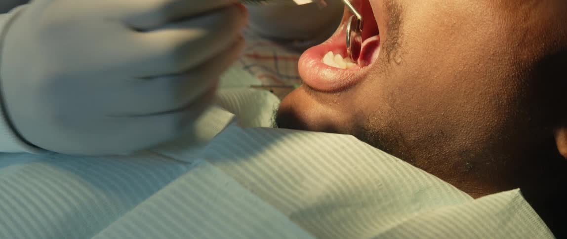 Dentist treats patient using mouth mirror and dental probe at clinic