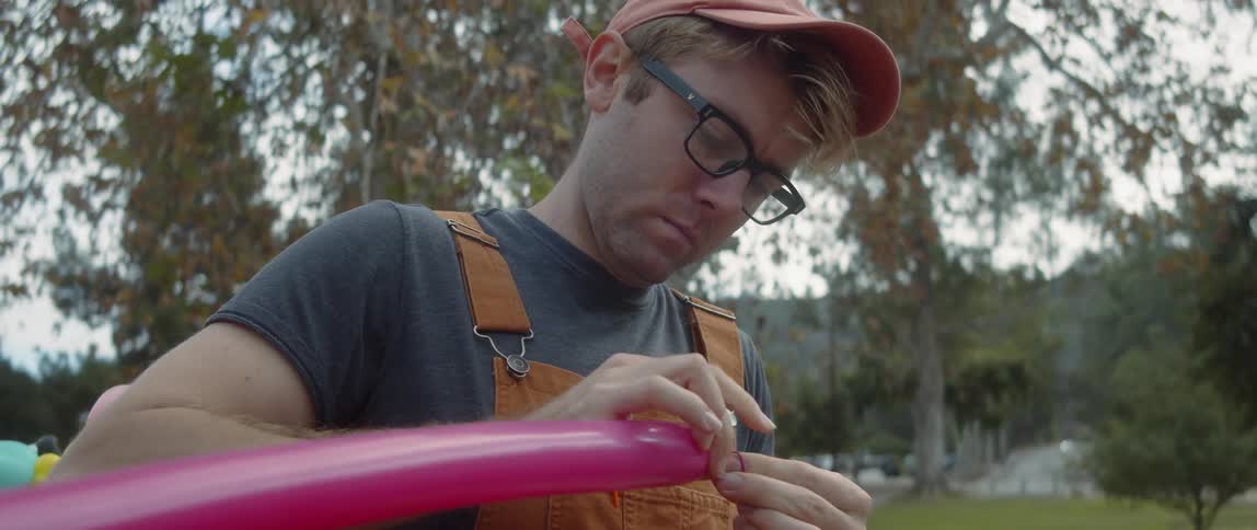 A man is making balloon animals in the park