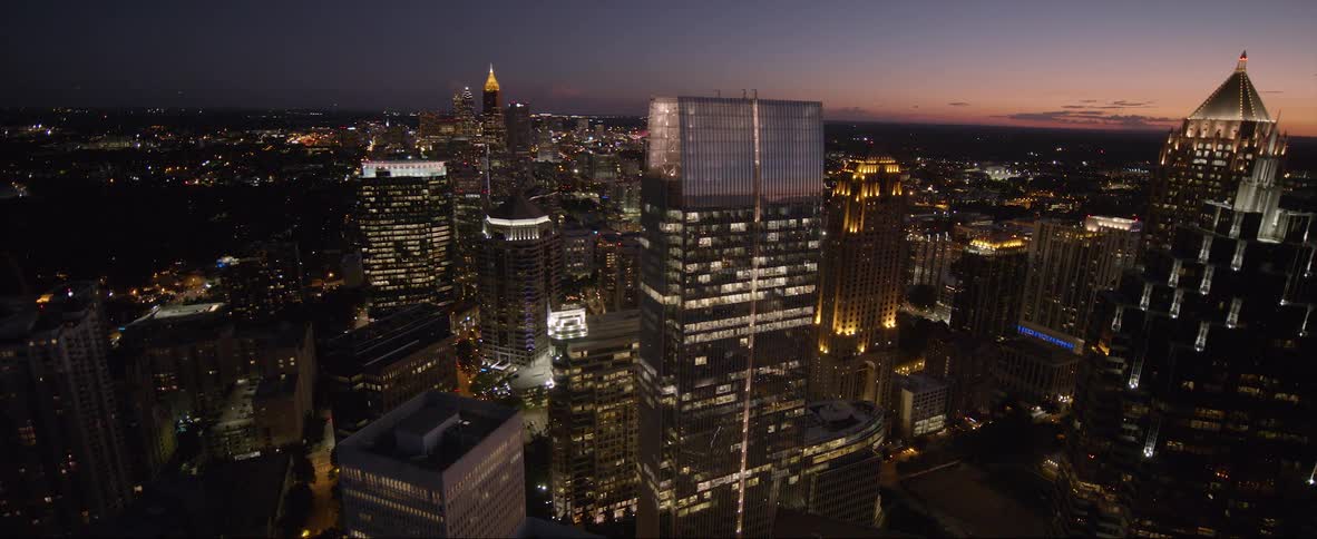Aerial view of illuminated buildings and skyscrapers in the city at dusk