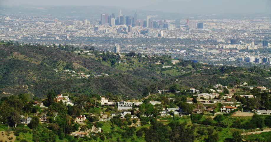 Aerial view of hills with buildings and distant city skyline