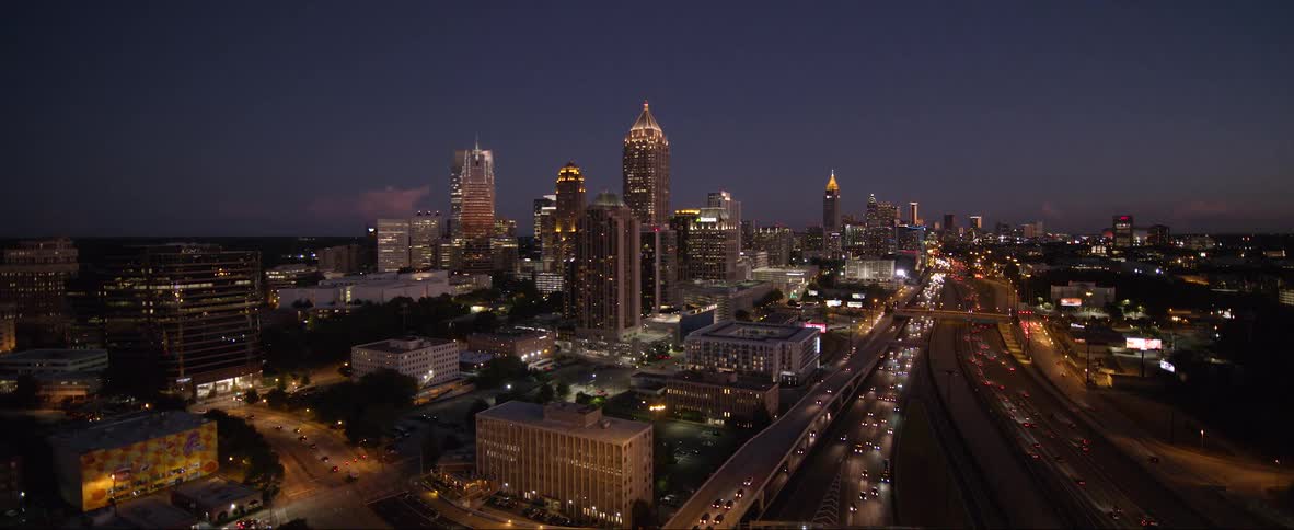Traffic flows down highway through downtown at night
