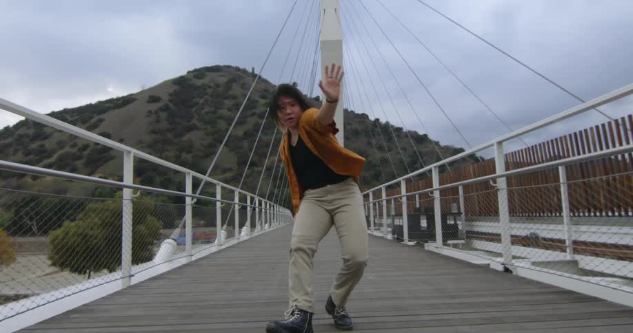 A teenager dances down a boardwalk