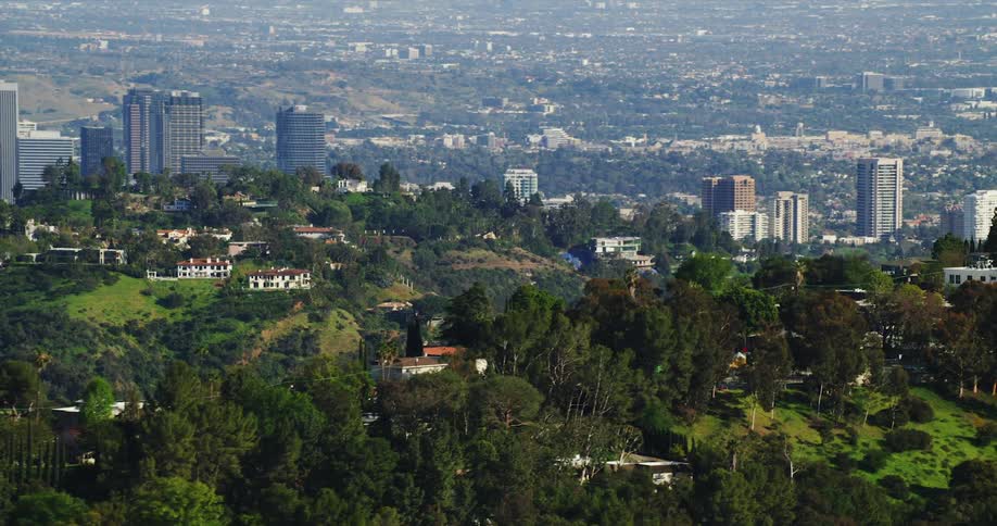 Aerial view of buildings on green hills overlooking skyline in the city