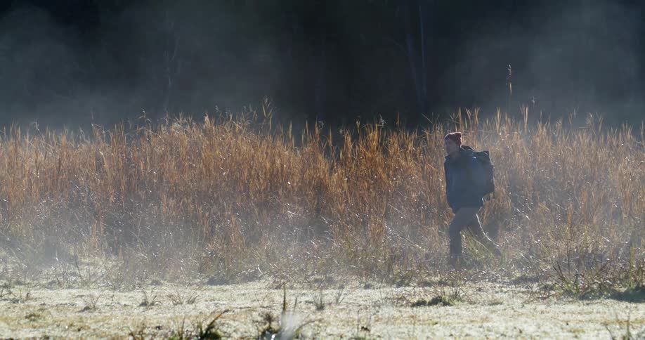 A white man is walking down a trail in the forest area