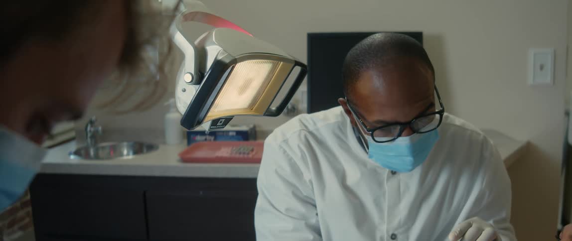 Dentist talks to dental assistant while examining patients teeth