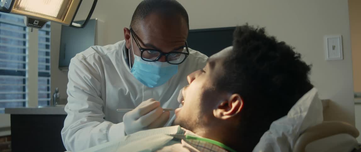 Dentist checks the a patient with his mouth open reclined on a chair