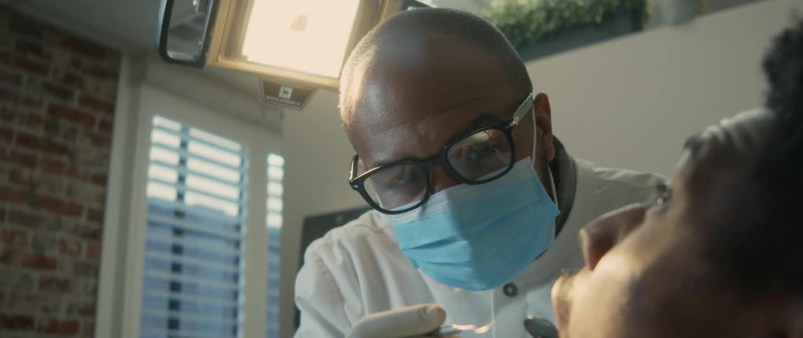 Dentist examines patient reclined in chair