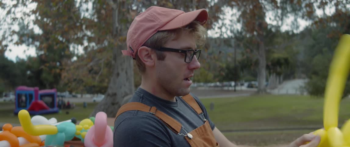 Man sitting in park makes balloon animals