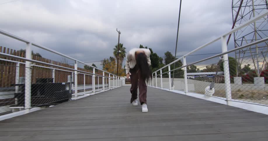 Female dancer dances backward on path near electric transmission tower