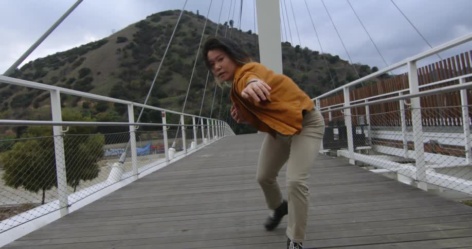 A young woman is dancing on a bridge in the middle of the day