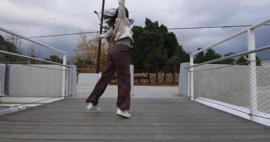 Young performer dances fluidly while running over a suspension bridge