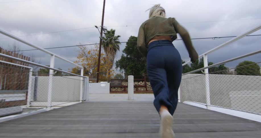Young performer dances fluidly while running over a suspension bridge
