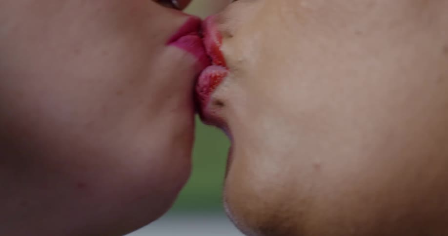 A pair of women share a kiss indoors during the day