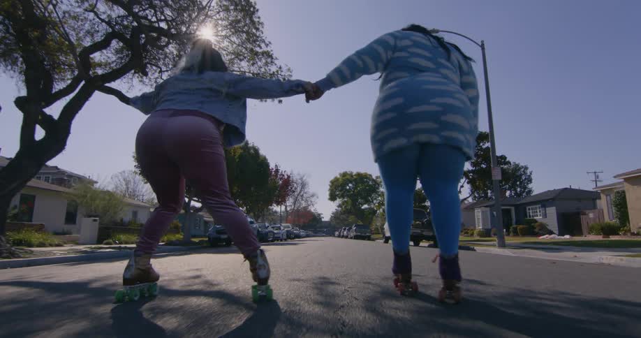 Two friends are rollerblading outside of there neighborhood