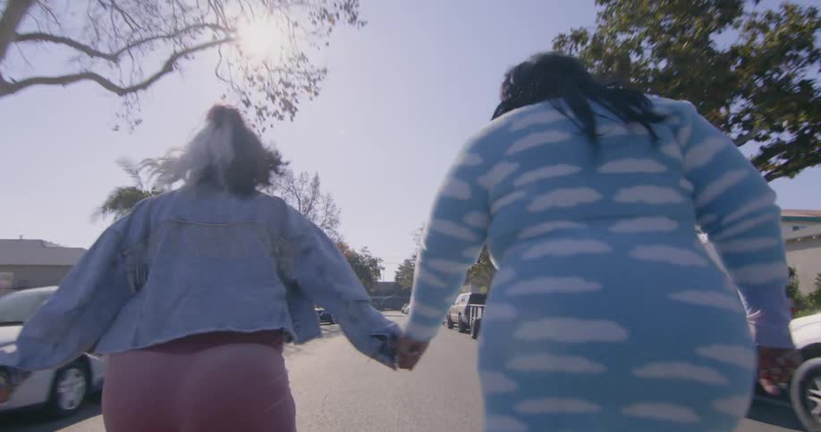 Two friends hold hands while roller skating on the neighborhood
