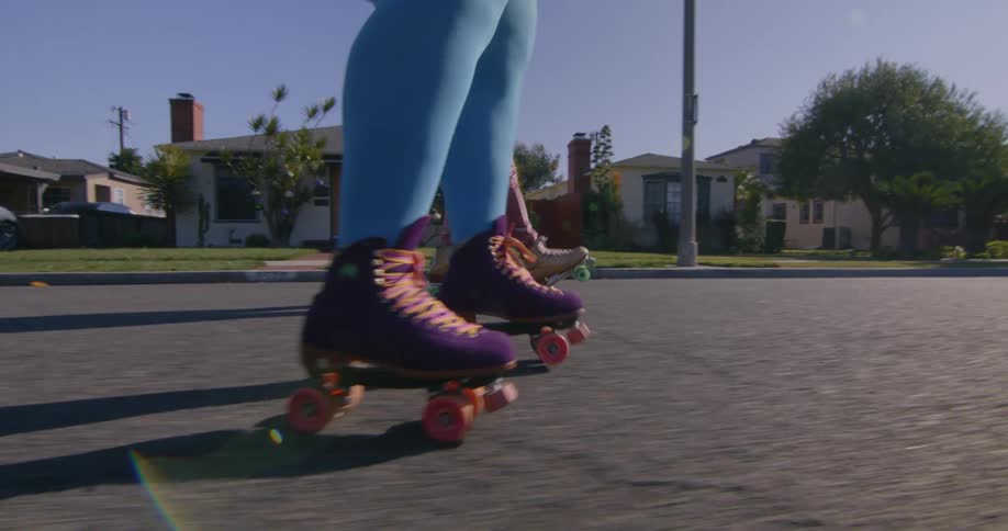 Two women are roller skating down the town street