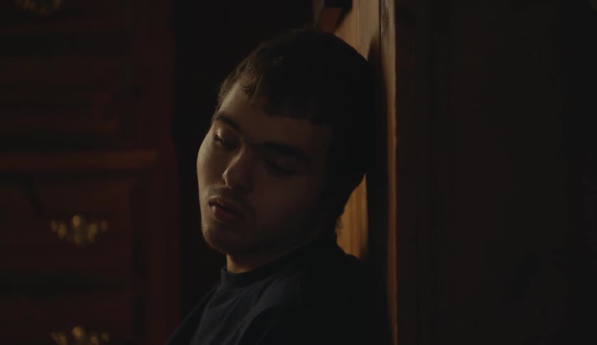A man looking sad is leaning against wood furniture