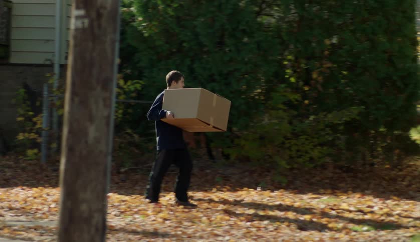 A teenage boy and mother are carrying boxes into there new home
