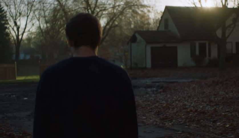 Young man walks towards the house on a chilly morning