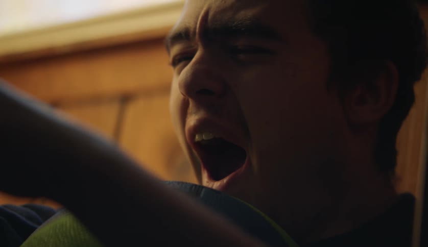 A teenage boy indoors yawns