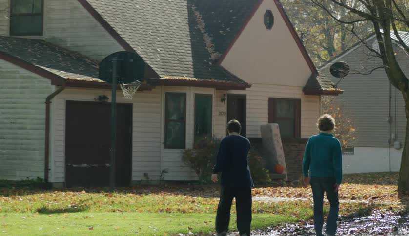 A woman has her hand on her sons shoulder as they walk to their house