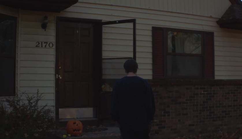 Man with dark blue sweater walks and enters house