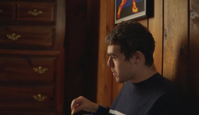 A teen is sitting down and eating a snack