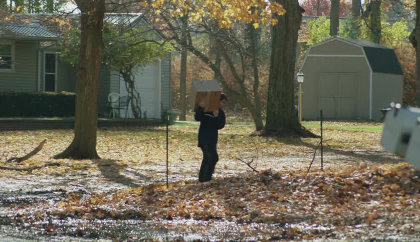 A teenage boy and his mother are carrying boxes out of a house to the street