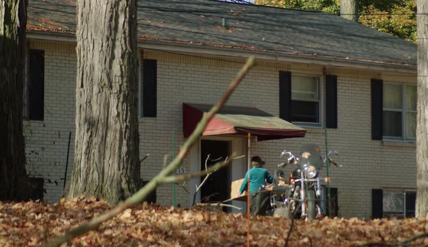 Woman carrying box to a front door then running with songrandson through the front yard