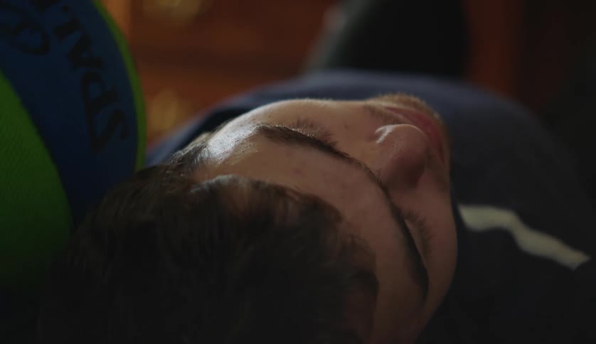 A young teenage boy is laying down in his bed