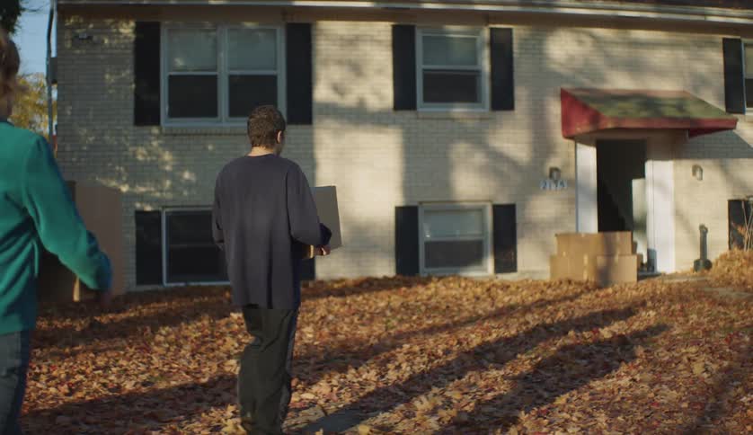 Grandmother and grandson carrying cardboard boxes into the house